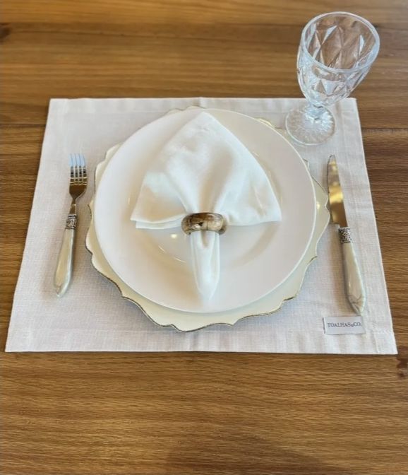 Guardanapo de tecido branco com argola de madeira sobre o prato