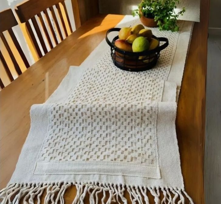 Caminho de mesa de macramê cru com franjas sobre mesa de madeira